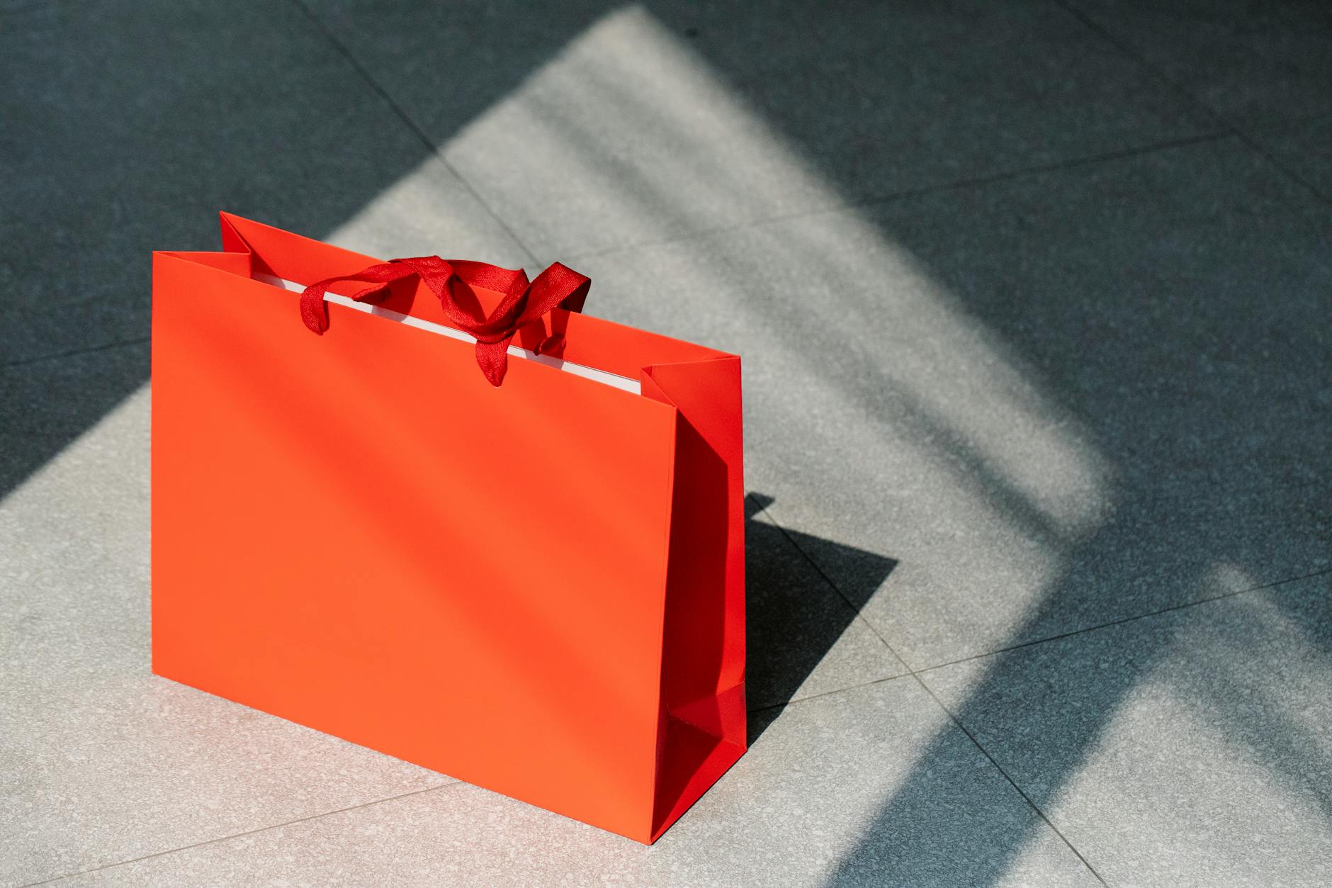 https://www.pexels.com/photo/red-paper-shopping-bag-on-gray-ground-7319125/