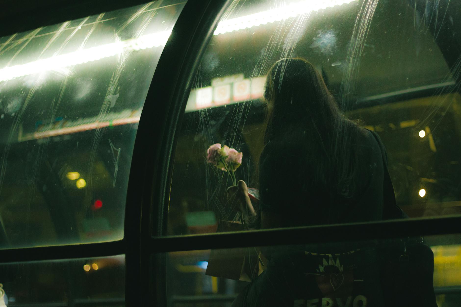 https://www.pexels.com/photo/back-view-of-a-woman-holding-flowers-sitting-at-the-station-in-a-city-at-night-24863170/